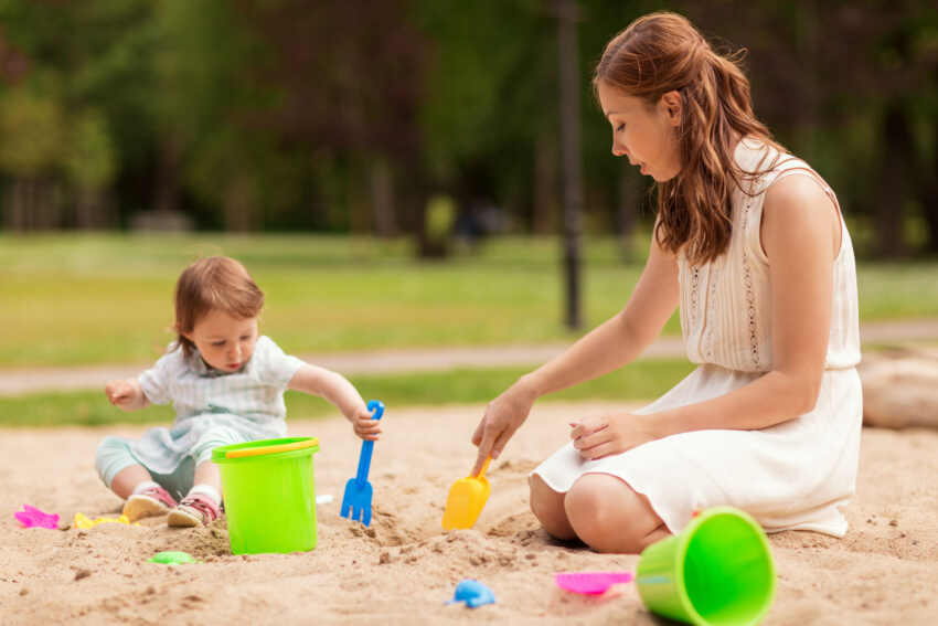 family childhood and parenthood concept happy mother and little baby girl with sand toys playing in sandbox at summer playground happy mother and