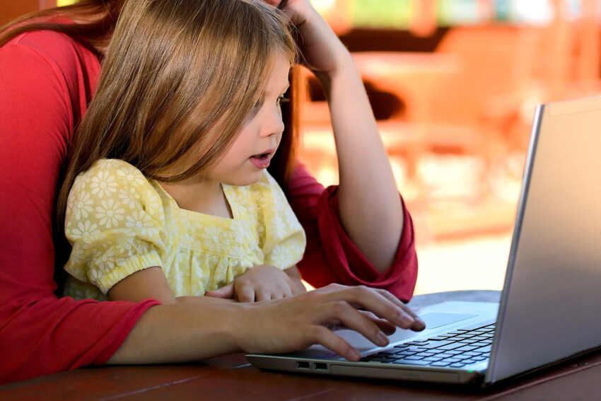child on laptop with mom